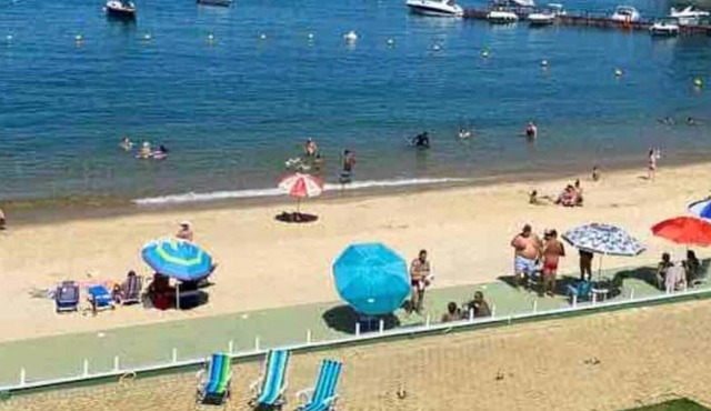 Foot in the sand with crystal clear water at Praia Grande in Angra