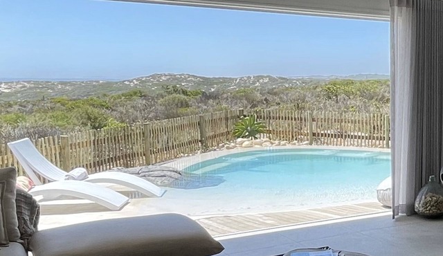 Tranquil haven: home in nature's embrace, where ocean and dunes unite.